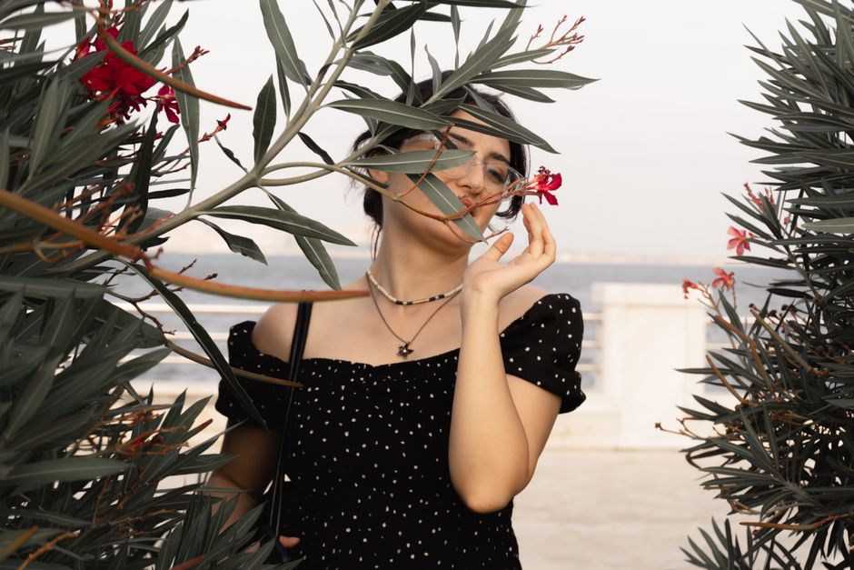Artistic portrait of a woman interacting with flowers by the seaside in Baku.