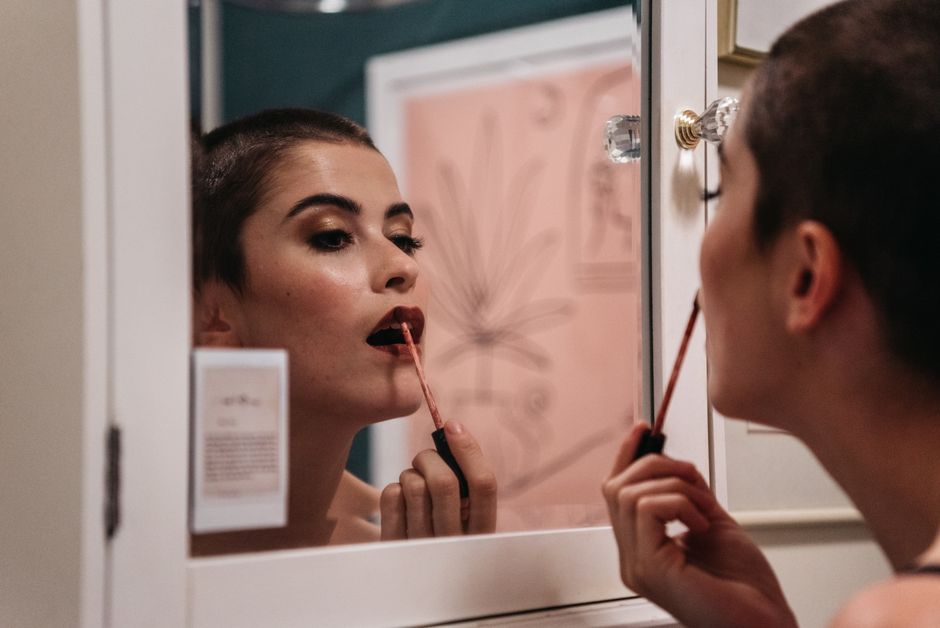 Woman applying lipstick in a mirror